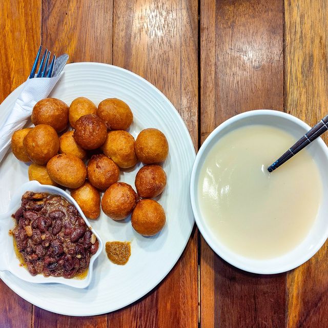 Des beignets accompagnés de bouillie et de haricots, posés sur une table en bois