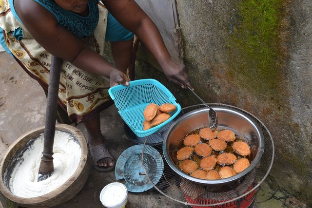 Une vendeuse retire des beignets de l'huile de friture