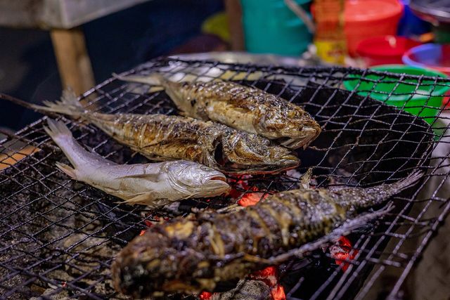Des poissons braisés sur un gril à charbon
