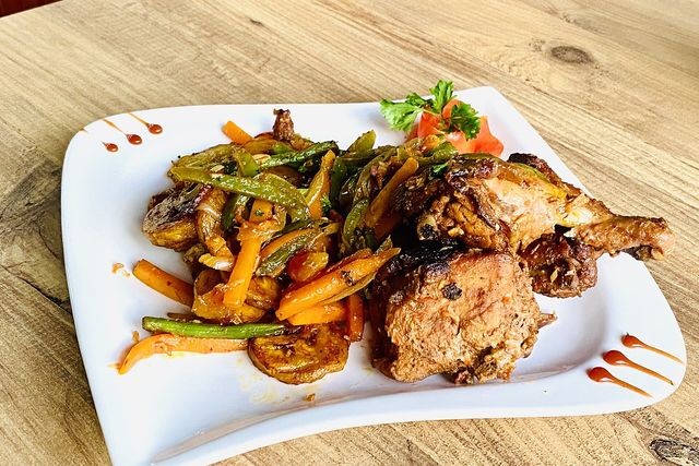 Un poulet DG servi avec des plantains sautés et des légumes