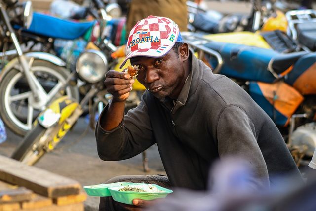 Un homme savoure une assiette de ndolè dans une rue de Douala