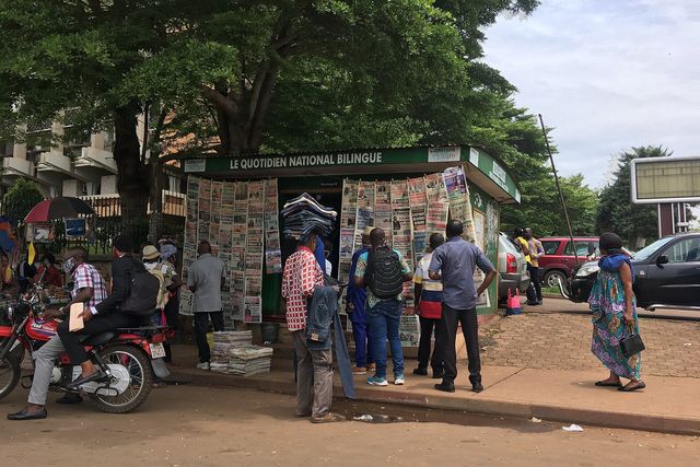 Un kiosque à journaux entouré de passants dans une rue de Yaoundé